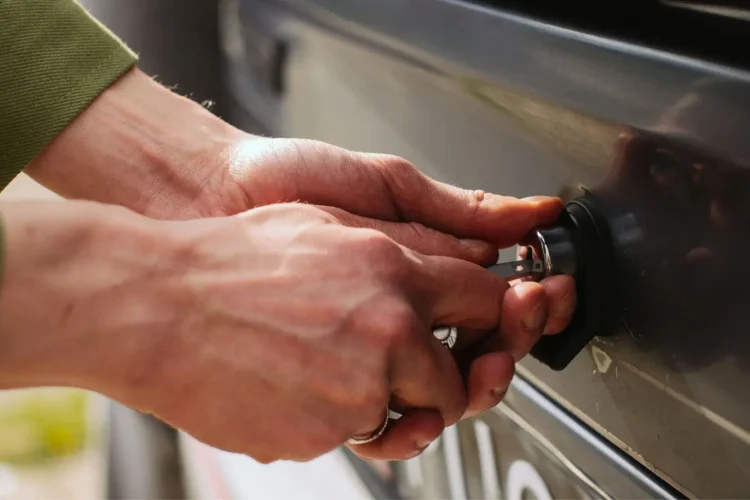 Gros plan sur des mains insérant une clé dans une serrure de voiture, image qui illustre les démarches après un vol auprès de la police et de l’assurance.