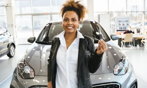 Personne tenant une clé devant un SUV neuf en concession, image qui illustre la question du délai de réception de la carte grise après l’achat d’un véhicule.