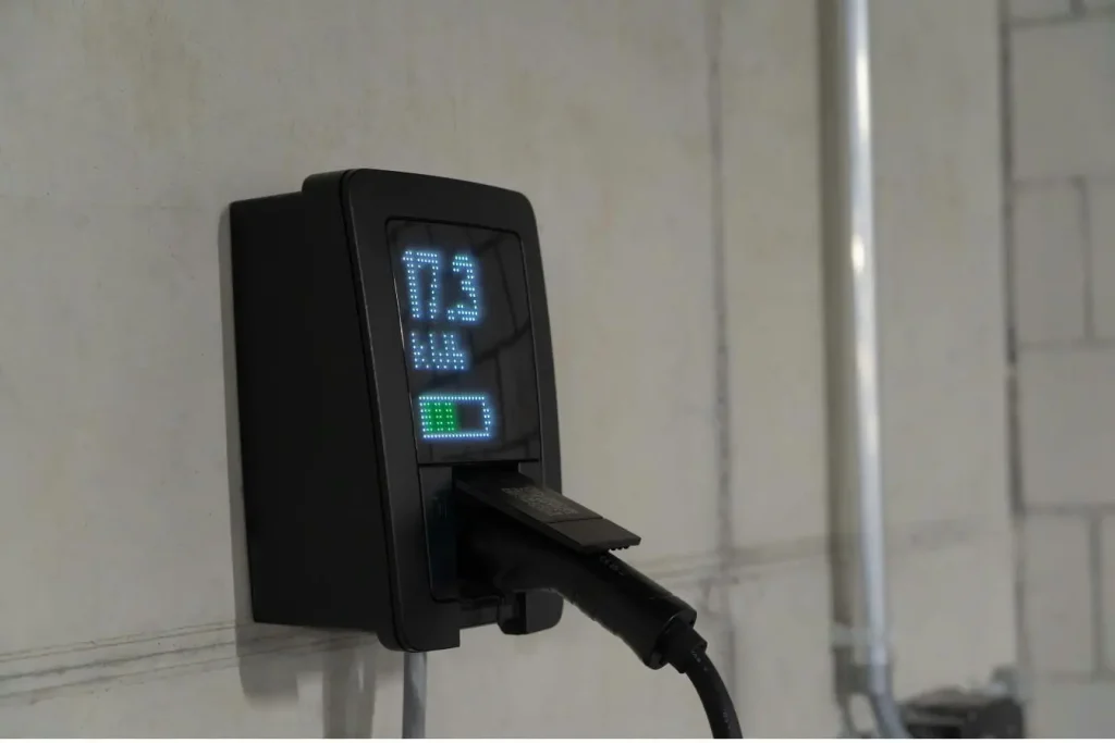 Borne murale affichant la charge en kWh, image qui illustre l’installation d’une IRVE à domicile et les aides financières disponibles pour réduire le coût.