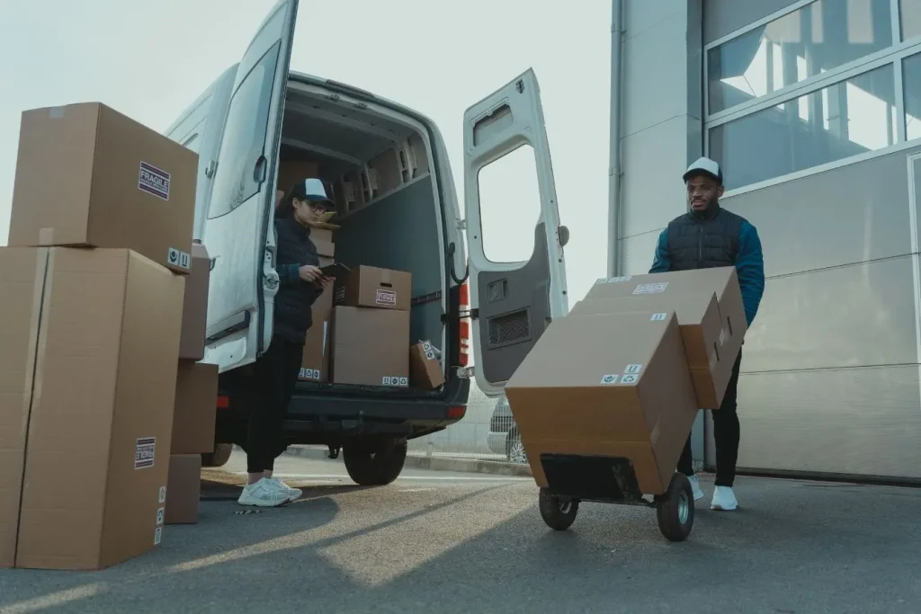 Employés manipulant cartons devant camion de livraison, image qui illustre l’avantage en nature lié à l’usage d’un véhicule de fonction.