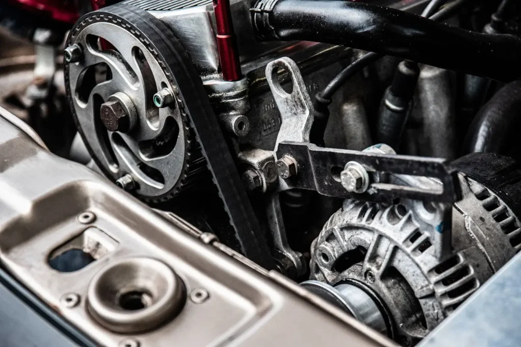 Gros plan sur compartiment moteur avec courroie crantée et poulie, image qui illustre la précision mécanique des boîtes à double embrayage.