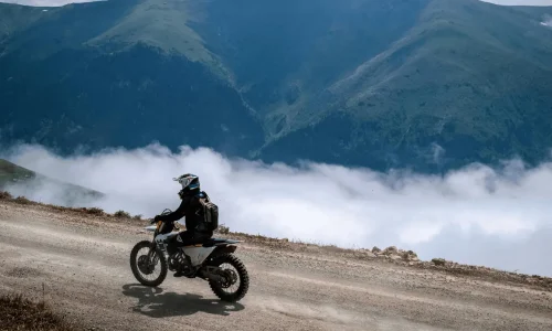 Pilote en moto sur piste montagneuse, illustrant le duel entre trail routier et roadster pour choisir style de conduite adapté.