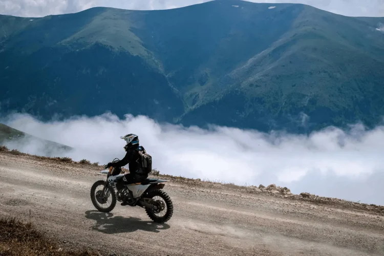 Pilote en moto sur piste montagneuse, illustrant le duel entre trail routier et roadster pour choisir style de conduite adapté.