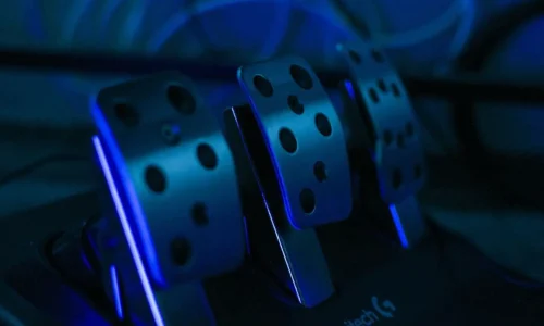 Gros plan sur pédales métalliques éclairées en bleu, reflet d’un problème de pédale d’embrayage qui descend seule et ses solutions mécaniques.