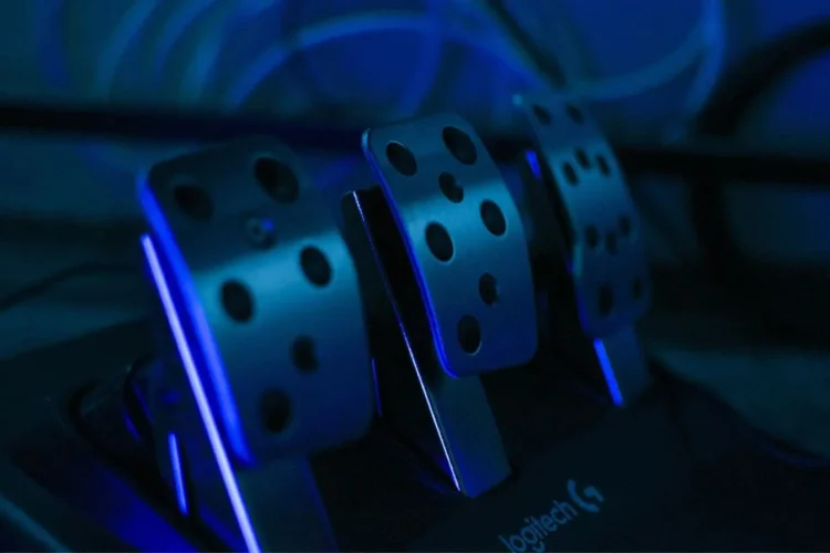 Gros plan sur pédales métalliques éclairées en bleu, reflet d’un problème de pédale d’embrayage qui descend seule et ses solutions mécaniques.