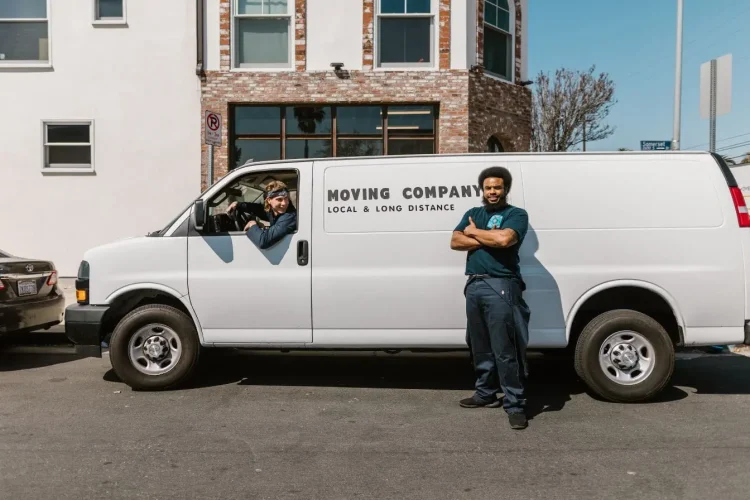 Camionnette blanche stationnée devant bâtiment avec employé, image qui illustre l’avantage en nature d’un véhicule de fonction.