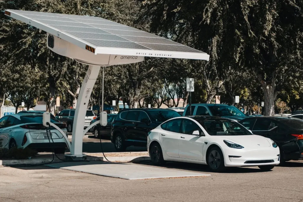 Parking avec borne solaire et voiture électrique branchée, reflet des facteurs qui modifient l’autonomie réelle.