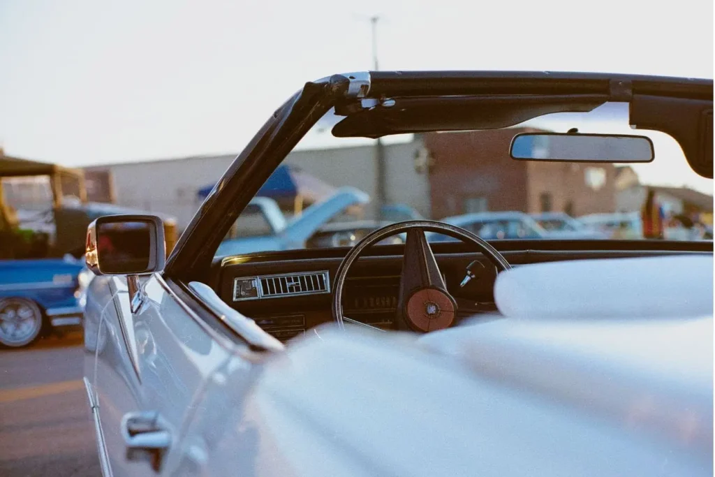 Intérieur d’un cabriolet blanc avec volant vintage et sièges clairs, image qui illustre le charme d’une microcar dans le contexte des voitures sans permis.