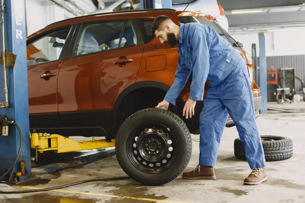 Atelier automobile avec véhicule sur pont hydraulique, reflet d’un avis sur les pneus increvables Michelin et leur résistance.