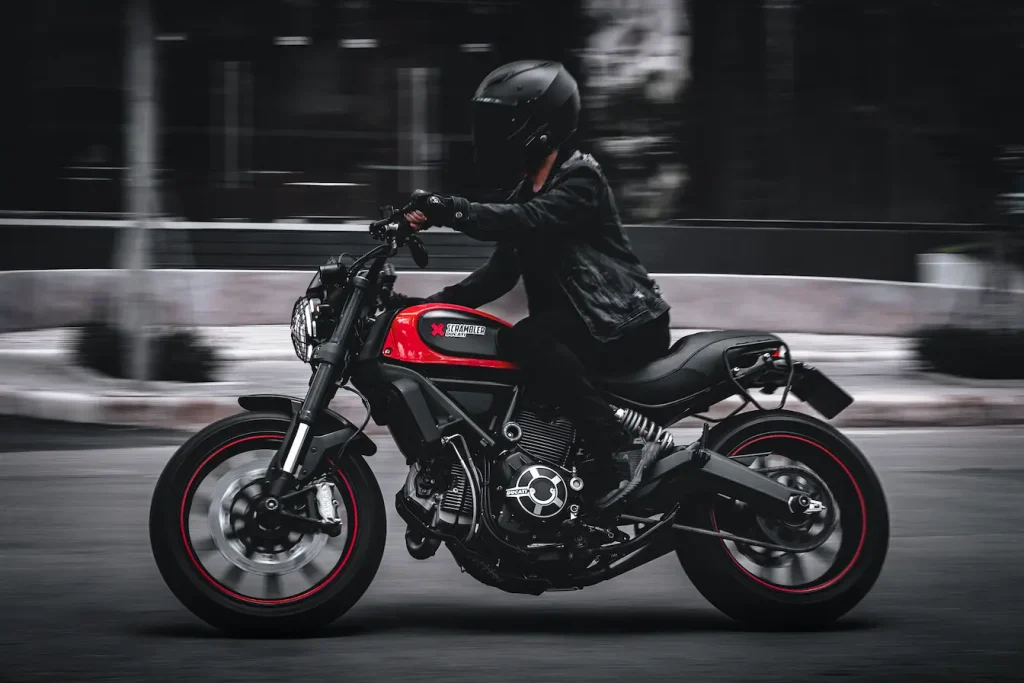 Scène dynamique avec pilote casqué sur moto rouge et noire, illustration typique du fonctionnement de la franchise en cas de vol.