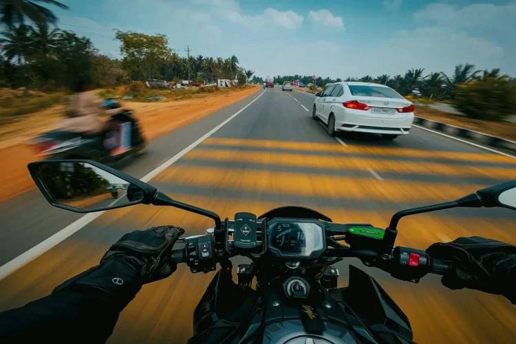Vue pilote sur moto avec route et voitures, reflet des signes d’un embrayage qui patine et des solutions mécaniques.