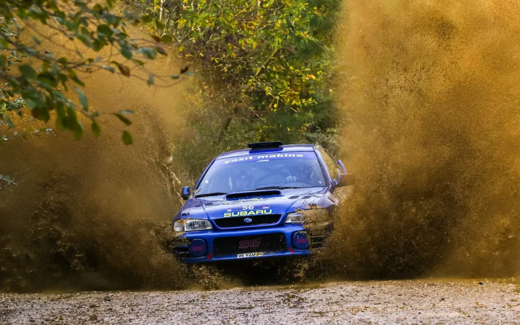 Voiture de rallye éclaboussant l’eau et la terre, reflet de la différence entre rallye‑raid et rallye classique.