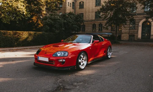 Voiture rouge sportive garée devant bâtiment ancien, image qui illustre la voiture la plus vendue en France en 2025.
