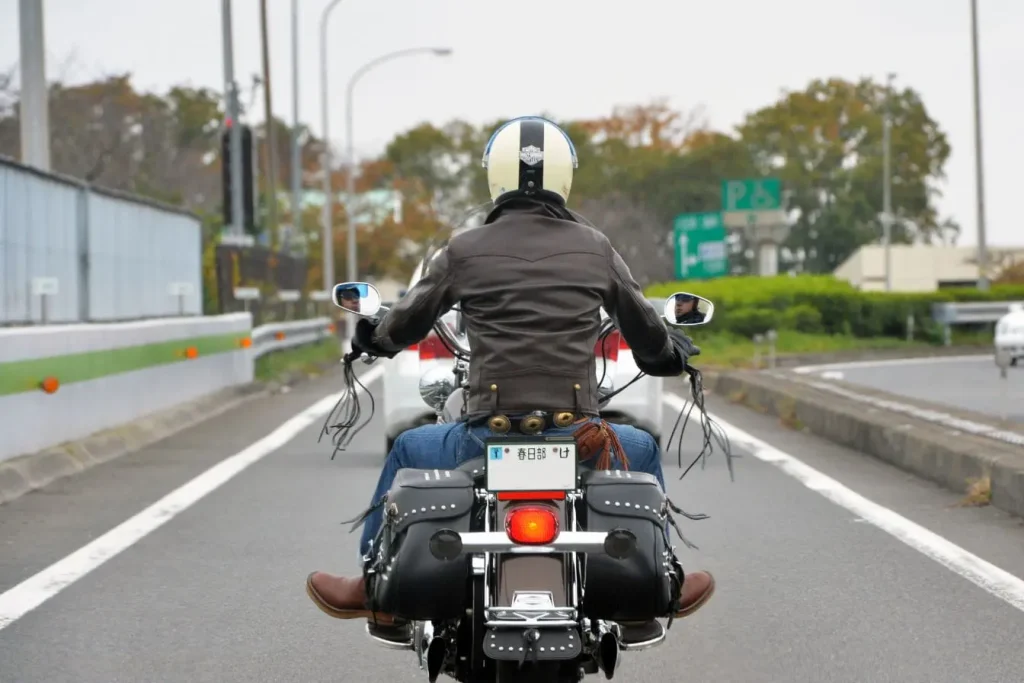 Conducteur en jean et bottes brunes chevauchant moto, symbole des pratiques liées à la durée de vie d’une batterie moto.