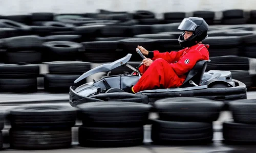 Pilote en combinaison rouge conduisant un kart noir sur piste, image qui illustre la question de l’âge minimum pour faire du karting.