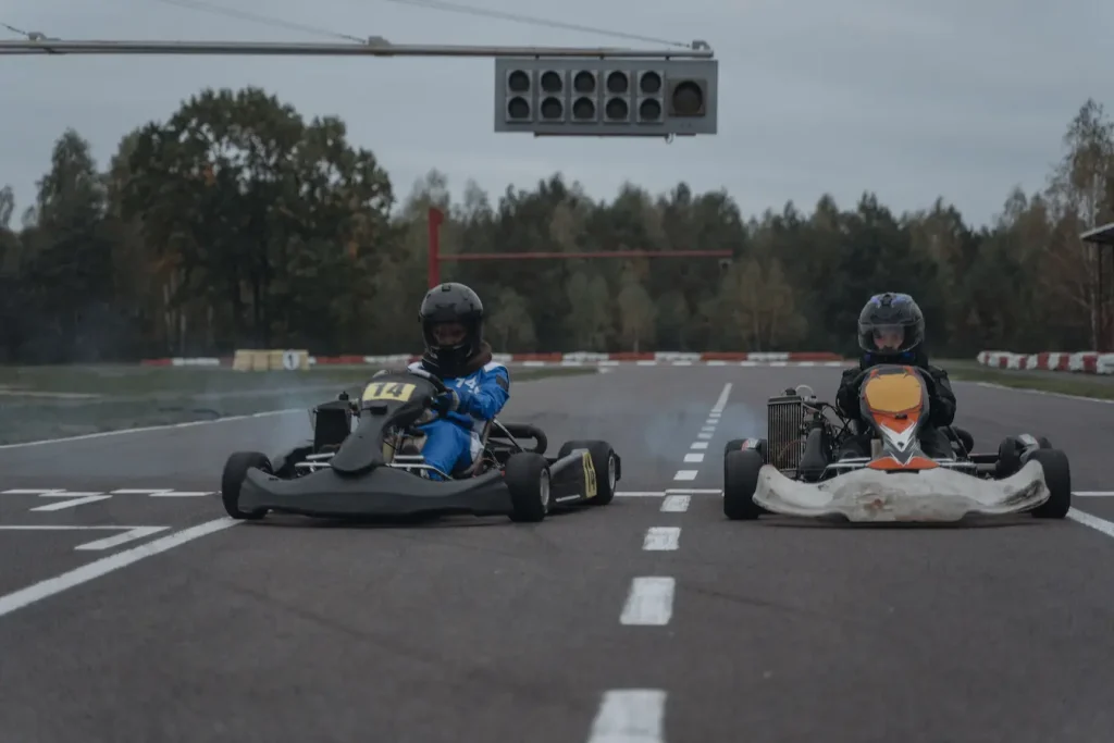 Deux pilotes en combinaison prêts au départ sur piste, image qui illustre la question de l’âge minimum pour faire du karting.