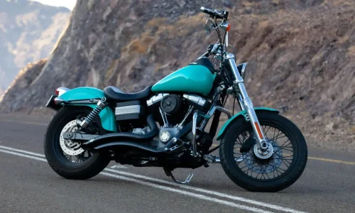 Moto turquoise posée sur route sinueuse, illustration typique de la meilleure moto routière pour débutant.