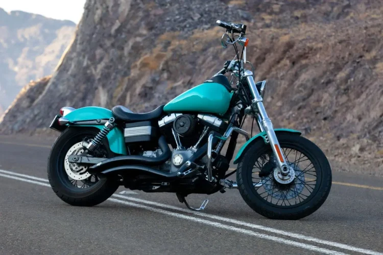 Moto turquoise posée sur route sinueuse, illustration typique de la meilleure moto routière pour débutant.