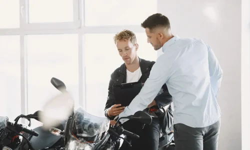 Deux personnes discutent devant motos noires en showroom, symbole des explications sur la franchise assurance moto en cas de vol.