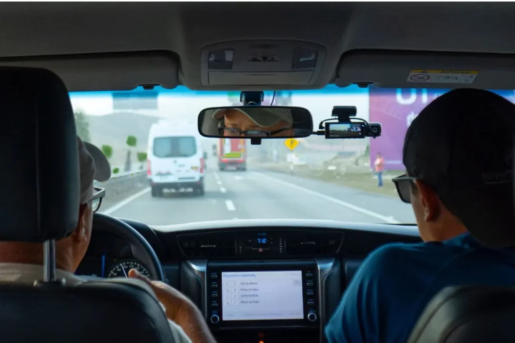 Vue intérieure d’une voiture sur autoroute avec caméra fixée au rétroviseur, reflet des coûts liés au remplacement pare‑brise et calibrage caméra.