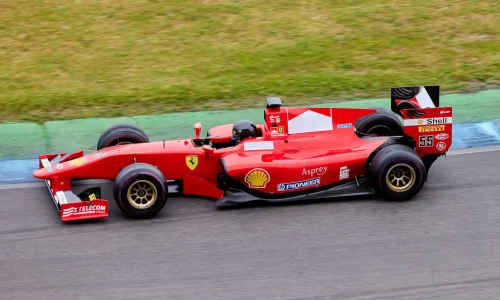 Voiture de course rouge filant sur piste, image qui illustre le pilotage sur circuit.