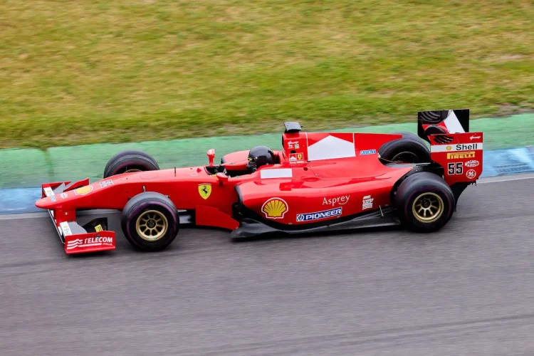 Voiture de course rouge filant sur piste, image qui illustre le pilotage sur circuit.