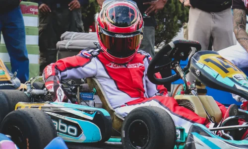 Pilote en combinaison rouge assis dans son kart numéro 14, image qui illustre le salaire moyen d’un pilote de course et la réalité derrière la passion.