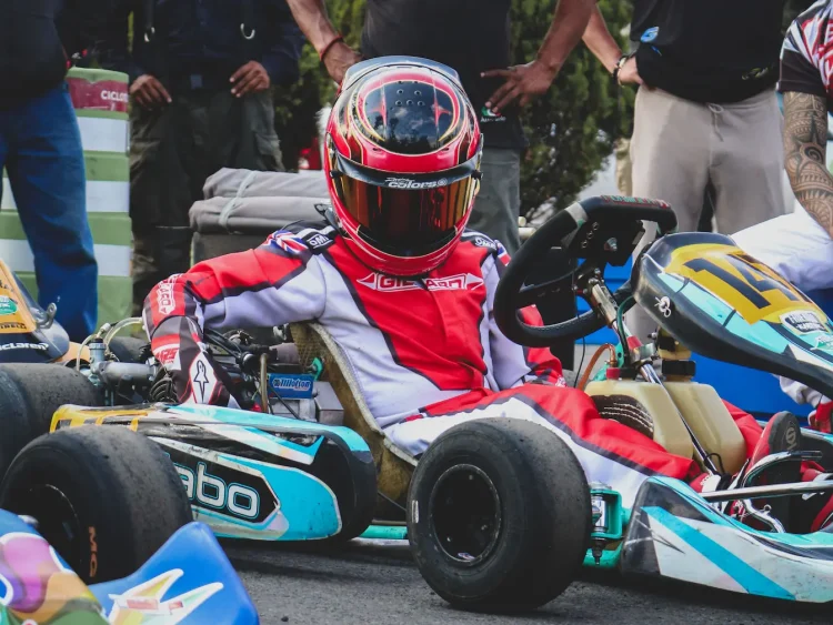 Pilote en combinaison rouge assis dans son kart numéro 14, image qui illustre le salaire moyen d’un pilote de course et la réalité derrière la passion.