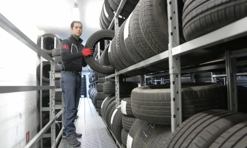 Personne manipulant un pneu dans un entrepôt organisé, image d’un avis sur les pneus increvables Michelin et leur fiabilité.