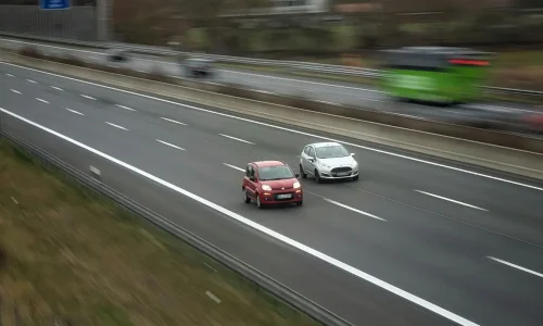Deux voitures côte à côte sur autoroute, reflet d’un bruit de sifflement pouvant apparaître à vitesse constante et nécessitant diagnostic.