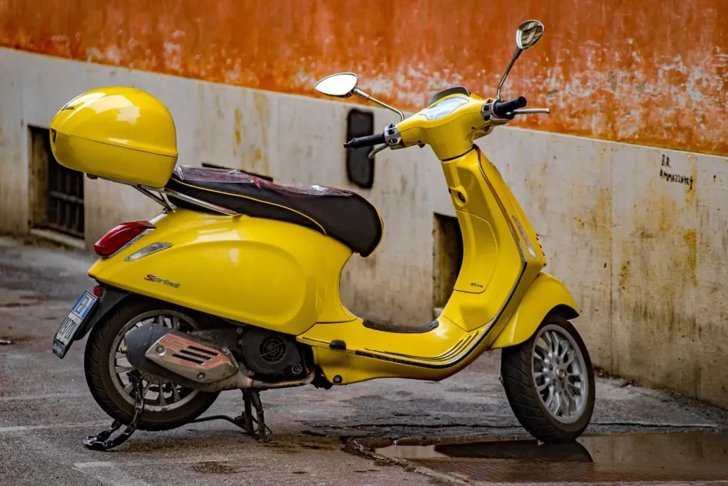 Scooter stationné sur sol mouillé avec reflet, symbole des décisions liées au prix d’un équivalent 125.