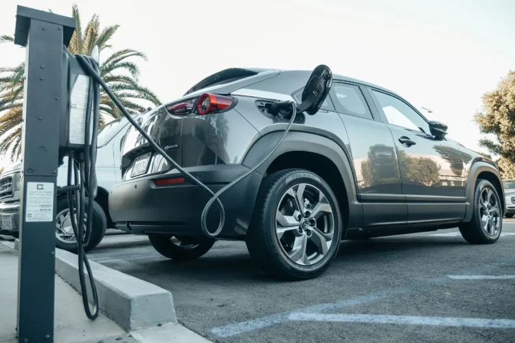 Voiture électrique grise branchée à borne de recharge, symbole des technologies hybrides rechargeables.