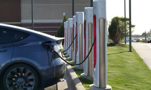 Voiture électrique branchée à borne Tesla blanche et rouge, symbole des aides pour installer une borne de recharge.