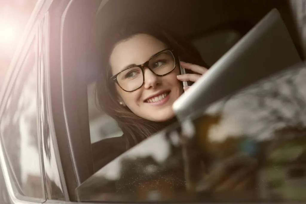 Gros plan sur passager en lunettes utilisant smartphone, image claire illustrant le confort du covoiturage.