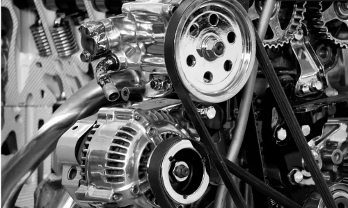 Des pièces métalliques de moteur astriquées reliées par des courroies, parfaites pour aborder l'usure des pièces et la durée de vie moyenne d'un embrayage.