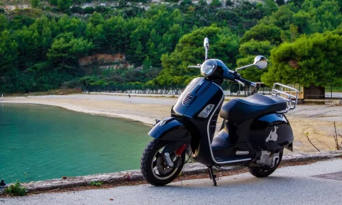 Scooter noir garé près d’un rivage turquoise, symbole des déplacements modernes et de l’autonomie moyenne d’un scooter électrique.
