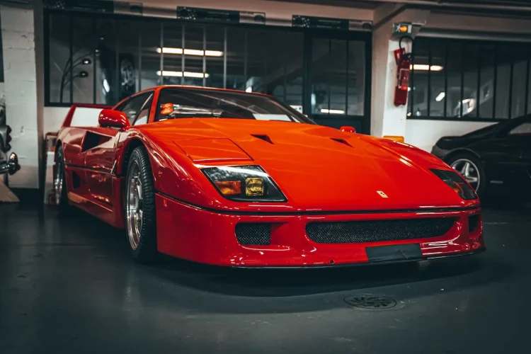 Ferrari F40 rouge garée en intérieur, symbole des voitures de collection nécessitant une assurance tous risques adaptée.
