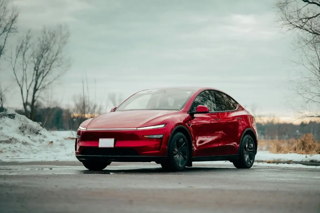 Voiture électrique rouge garée sur route humide avec neige, symbole des interrogations sur la durée de vie moyenne d’une batterie.